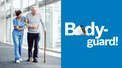 Ein Gang mit einer großen Fensterfront, durch die die Sonne hereinscheint. Eine Frau in hellblauer Arbeitskleidung und mit Stethoskop um den Hals hat sich bei einem alten Mann mit Stock eingehakt und führt diesen.